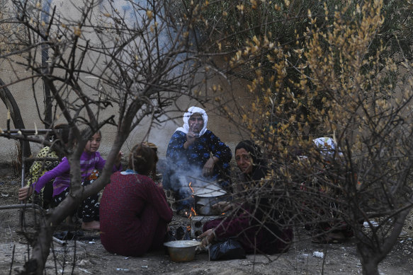A family who fled Ras al-Ain sit round a fire in Tal Tamr.