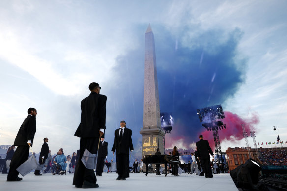 Artists wearing black suits, representing mainstream society, perform during the opening ceremony for the 2024 Paralympics as the colours of the French flag explode into the Parisian sky.
