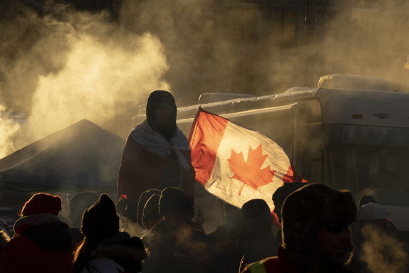 A protester stands on a barricade as trucks continue to block the downtown district in protest of COVID-19 restrictions, in Ottawa, Ontario.