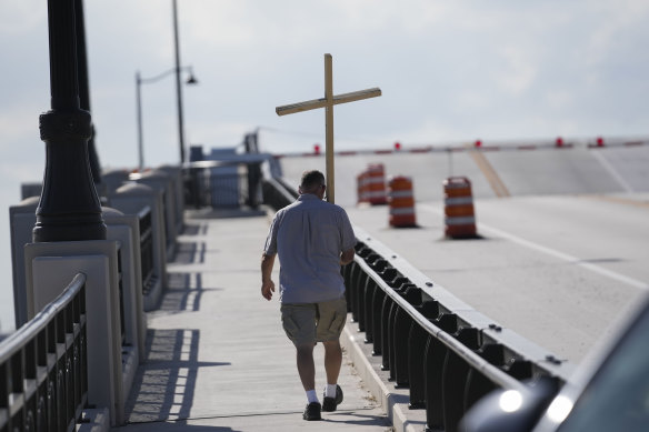 A supporter of former President Donald Trump walks with a cross from outside his Mar-a-Lago estate over a bridge to West Palm Beach, Florida last month.