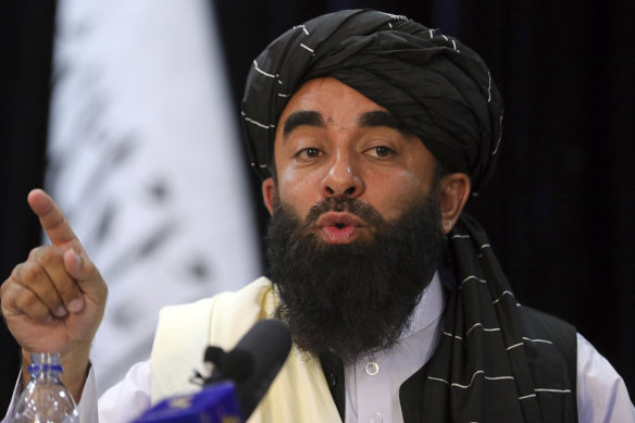 In front of a Taliban flag, spokesman Zabihullah Mujahid speaks at the Taliban’s first news conference during which he said women would not be mistreated.