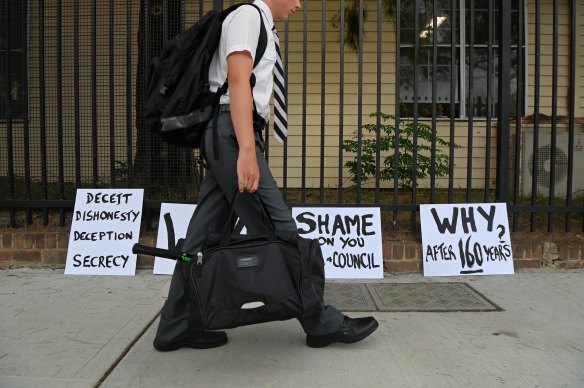 A Newington College student walks past signs protesting against the school’s plan to become co-ed by 2033.