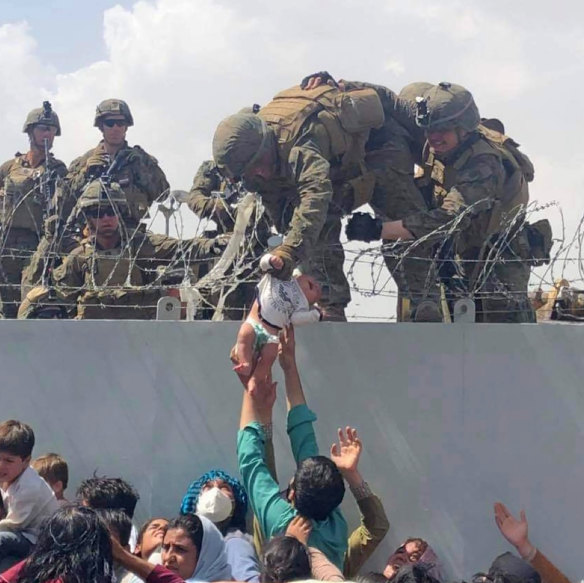 A baby is lifted across a wall at Kabul Airport in Afghanistan by US soldiers. 