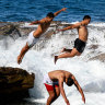 Swimmers leap off Giles Baths in Coogee on Sunday.
