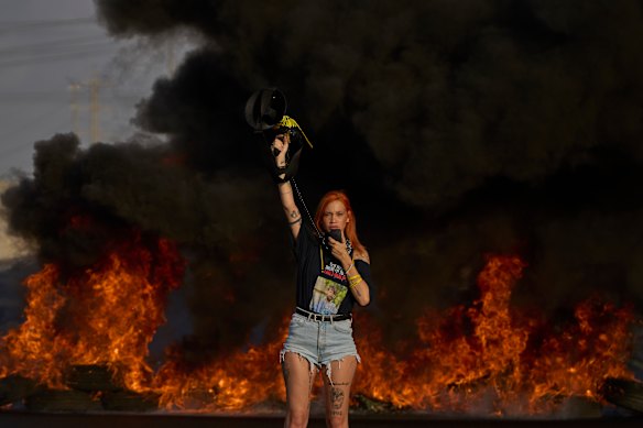 An activist blocks a highway during a protest demanding the immediate release of hostages held by Hamas and calling for the Israeli government to reverse its decision to take over Gaza City and other areas in the Gaza Strip, near the city of Lod, Israel.