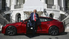 Donald Trump steps out of the red Model S he purchased to show solidarity with Elon Musk.