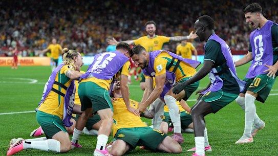 Connor Metcalfe is swarmed by Socceroos teammates.