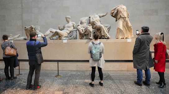 Visitors look at ancient sculptures that are part of the Parthenon Marbles at the British Museum in London.