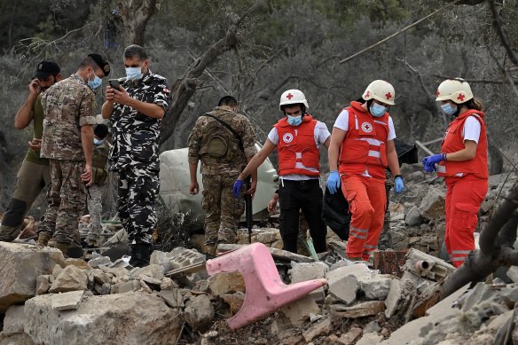 Red Cross members and authorities sift through the wreckage at the blast site that killed at least 23 people.