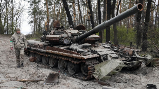 A Ukrainian soldier walks past a Russian tank after recent battles at the village of Moshchun close to Kyiv.