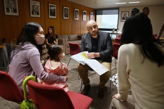 Mascot Towers owners Karee Chan with her daughter Cathleen Chan, age 2, and Stu Carr look through the letters residents have written to Premier Dominic Perrottet about their plight. 