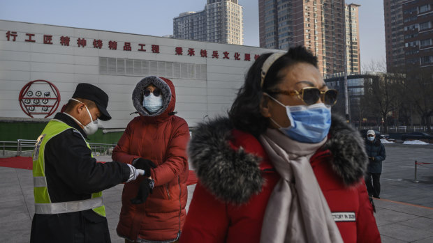 A Chinese woman wears a protective mask as she has her temperature checked entering a park in Beijing. 