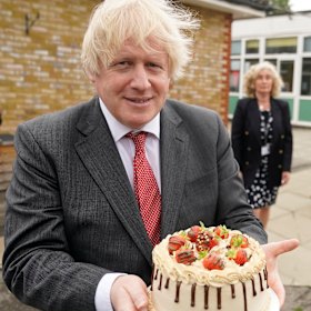 Johnson holds up a birthday cake - baked for him by staff during a school visit in June 2020.
