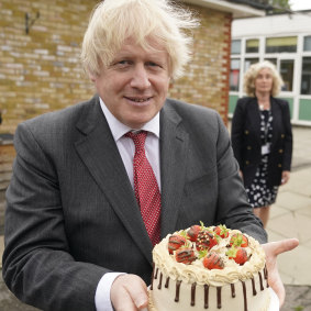 Johnson holds up a birthday cake - baked for him by staff during a school visit in June 2020.