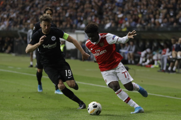 Arsenal's Bukayo Saka (right) runs the ball as Frankfurt's David Abrahim hovers.