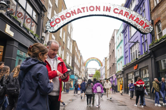 People check the alarm while in Carnaby Street in London. 