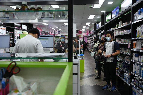 Cabramatta pharmacist Quinn On, at work on the left, worries he will waste his Moderna shots.