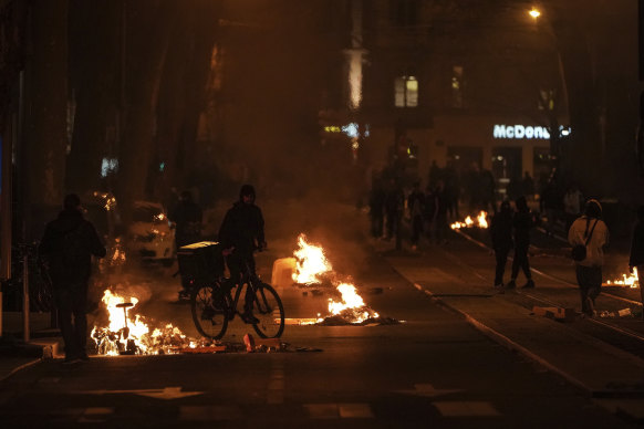 A man passes by fires set by protesters in Lyon, central France, after parliament adopted the divisive pension bill.