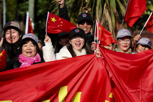 Supporters of the Chinese government wave Chinese flags outside Government House prior to an official welcome ceremony.
