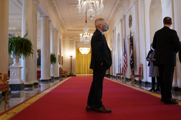 Dr Anthony Fauci stands in a hallway before an event with President Joe Biden on the coronavirus at the White House