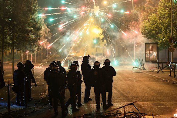 Police stand amid firecrackers on the third night of protests.