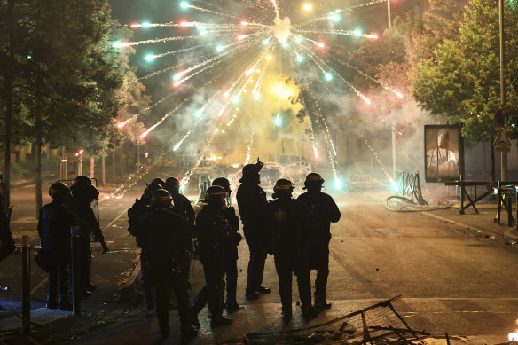 Police stand amid firecrackers on the third night of protests.