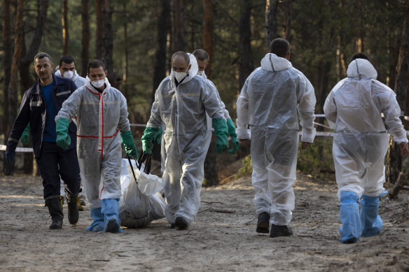 Workers carry bodies found in a mass grave near the city of Izium this month which was recaptured during a Ukrainian counter-offensive.