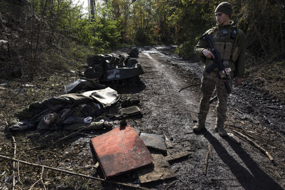 Ukraynalı bir asker, 1 Ekim 2022'de Ukrayna'nın Kupiansk kentinde yerde yatan bir Rus askerinin çürümüş cesedine bakıyor. 