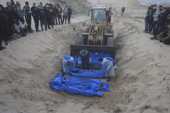 Bulldozer unloads the bodies of Palestinians killed in the north of the Gaza Strip and turned over by the Israeli military during a mass funeral in Rafah on Tuesday.