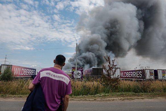 An employee looks at a plume of smoke rising during a fire at Russian e-commerce firm Wildberries’ logistics complex near the town of Podolsk, outside Moscow overnight.