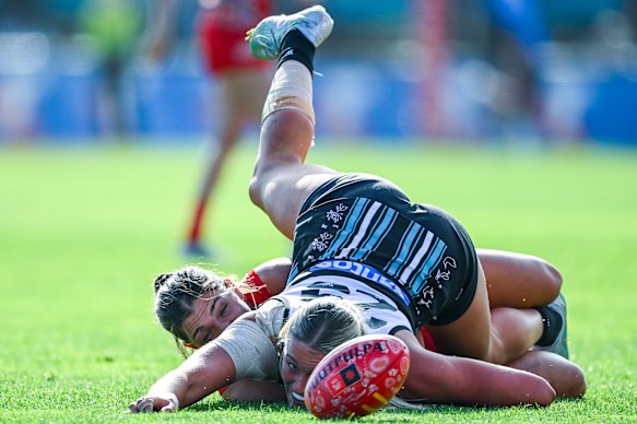 Darcie Davies of the Suns and Matilda Scholz of the Power tangle while chasing the footy.