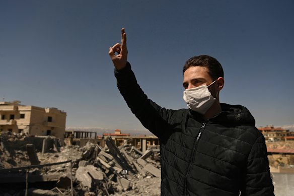 Adam Shreif dá sinal de vitória em frente à casa de sua família, que foi destruída por um ataque aéreo israelense em Douris, no Líbano.