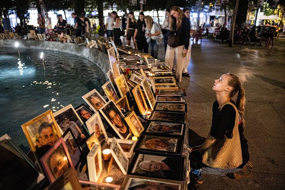 Katya Emelianova berlutut di samping potret Eden Gez yang terbunuh di Nova Festival pada 7 Oktober 2023.