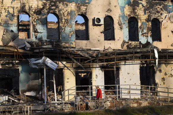 Bir kadın, Ukrayna'nın İzium kentinde yıkılan bir binanın yanından geçiyor.