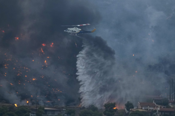 A helicopter dumps water on fires in Kalamaki, about 60 kilometres west of Athens.