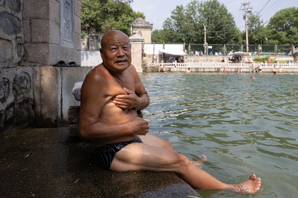 Sun Zhaoxiang, 82, a former serviceman and construction worker, splashes himself with the cool water from the canal. 