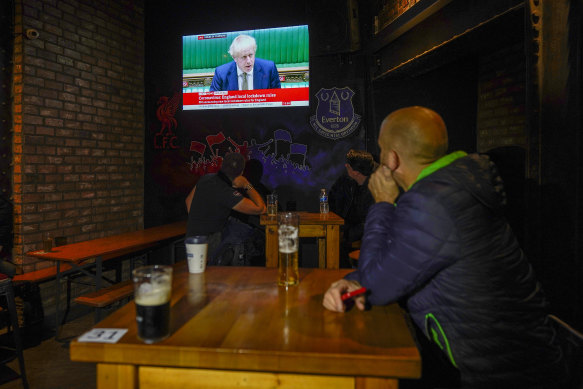 Locals in Liverpool watch Prime Minister Boris Johnson's address to Parliament on Monday. The city will go into tier-three lockdown under England's new system of restrictions.