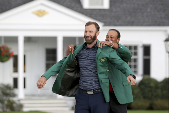 Johnson is presented the green jacket by Tiger Woods.
