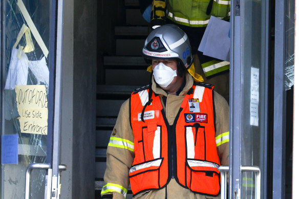 A Fire Service staff member walks past an “out of order” sign at the front entrance of Loafers Lodge.