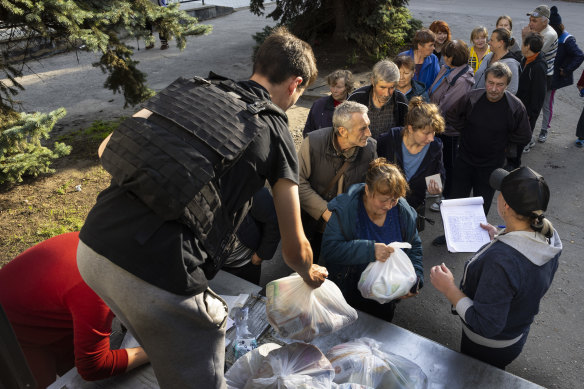 People wait in line for humanitarian aid from Globee International agency on October 1, 2022 in Kupiansk, Ukraine. The city has been successfully captured by Ukrainian Armed Forces pushing back the Russians.