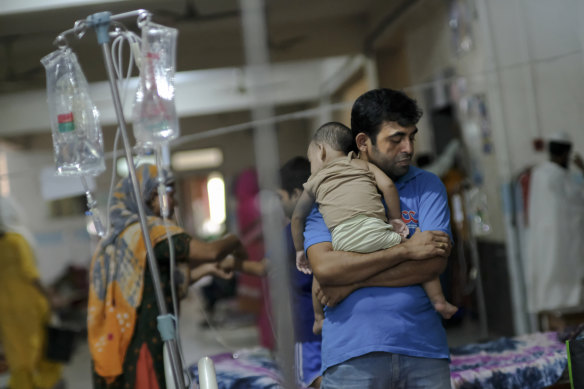 A man comforts his child suffering from dengue at Mugda Medical College and Hospital in Dhaka, Bangladesh.