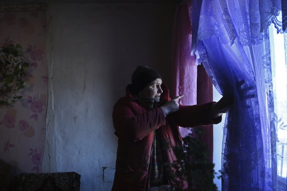 Olena Miroshnychenko, 45, looks out the window that was destroyed when mortars landed in the backyard of her home in Kamyanka village on the contact line in eastern Ukraine. 