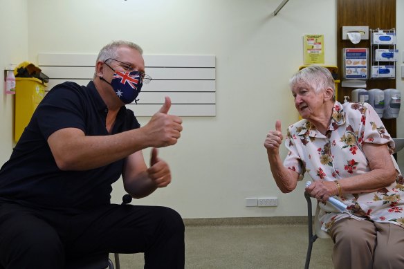 Scott Morrison (left) and Jane Malysiak (right) gesture after receiving their COVID-19 booster vaccination.