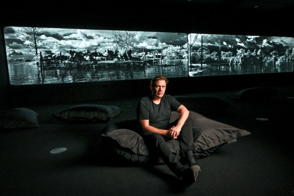 Artist Richard Mosse sits in front of the 20 metre-long screen which is playing his new work, Broken Spectre.