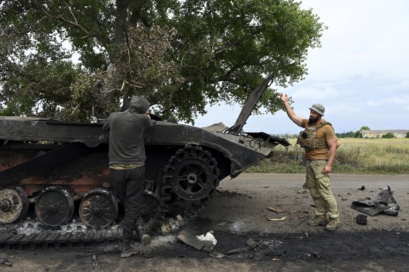 Two Ukrainian soldiers inspect a destroyed tank on a road near Siversk in the Bakhmut Raion of the Donetsk Oblast. 