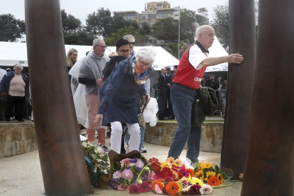 Jan and Alan Roberts lay a flower and hug the Coogee statue in memory of their son Ben, at the 20th anniversary of his death.