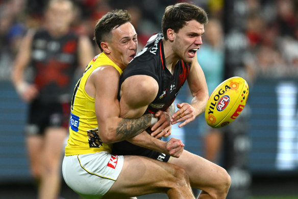 Jordan Ridley of the Bombers handballs whilst being tackled by Rhyan Mansell of the Tigers.