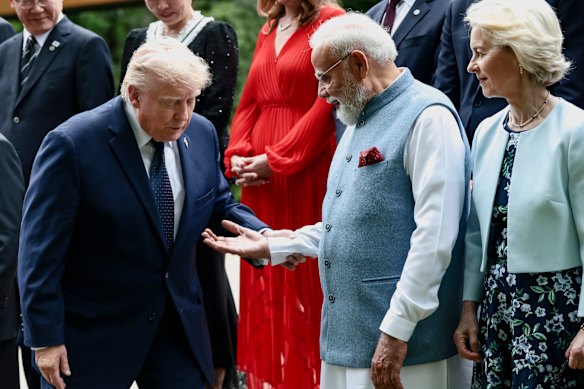Il primo ministro indiano Narendra Modi offre la mano a Donald Trump durante una foto di famiglia al G7.