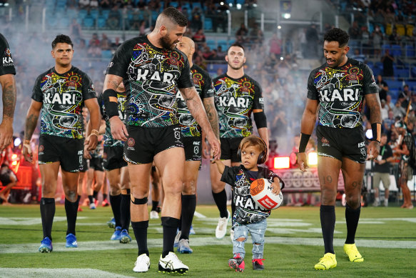 Quaden Bayles leads the Indigenous All Stars on to the field with captain Joel Thompson.
