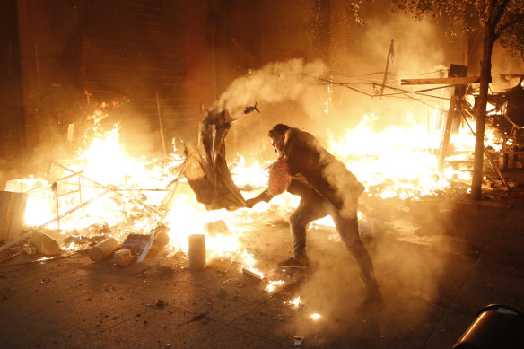 A protester attempts to extinguish the flames after his tent was set on fire.